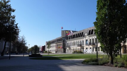 Panevezys city downtown square, on the right - town hall decorated with flags, blurry distant people.