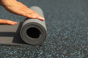 Man hands unrolling yoga mat before practice at sports ground. Outdoor. Copy space. Yoga, sport, healthy lifestyle concept. Close up.