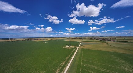 Elektrownia wiatrowa - wiatraki na tle błękitnego nieba z chmurami