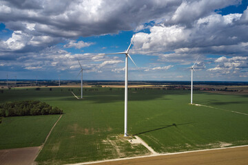Elektrownia wiatrowa - wiatraki na tle błękitnego nieba z chmurami