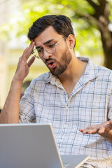 Displeased Indian man using laptop typing browsing working, loses becoming surprised sudden lottery...