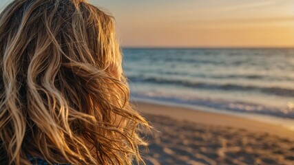Woman with wavy hair gazing at ocean sunset
