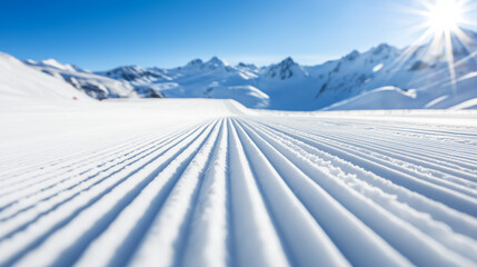 New groomed ski paste or slope. Lines in snow with sunny mountains background. Winter skis concept 
