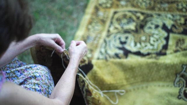 Woman hands knitting stitch overlock on an old carpet edge