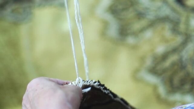 Woman hands knitting stitch overlock on an old carpet edge closeup