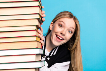 Close up portrait of cheerful glad clever girl wear stylish clothes peek out book isolated on blue color background