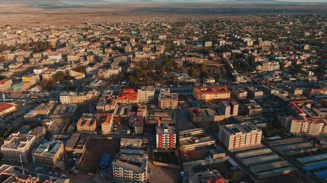  An aerial view of a bustling urban landscape, bathed in the warm glow of sunrise, showcasing the city's intricate network of streets and buildings