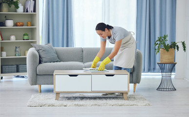 Cleaning, tidy and woman by table in living room for organising, remove dirt or doing chores....