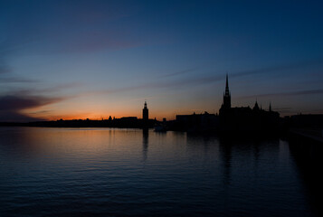 Obraz premium Panoramic view of Stockholm City hall at sunset with orange sky and calm water reflection. Scenic skyline of the Swedish capital at dusk. 