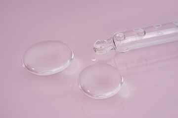 Macro shot of pipette drop of serum test on a pink background