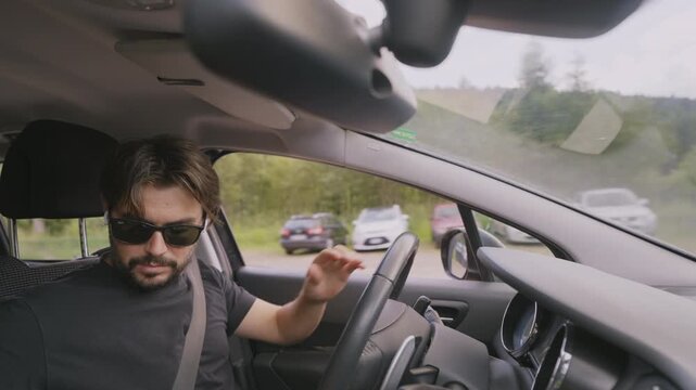 Young man with sunglasses putting wireless earphones while driving to answer a call. Side medium shot