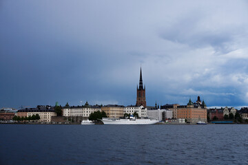 View of a city by the river against cloudy sky