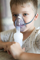 The Caucasian boy makes inhalation with a nebulizer inhaling medicines into his lungs....