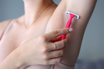 The girl removes unwanted body hair with a razor in the interior of the room. Removal of unwanted hair on the legs