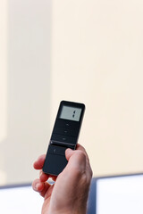 Remote control for window blinds. Man holds in his hand black remote control panel with display and operate motorized roller shades. Radio control electric blinds close-up.