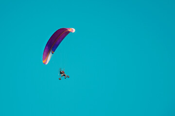 Paraglider flies with a parachute on an air motorcycle with a propeller. Man paragliding with motorized trike under clear sky. Air sports