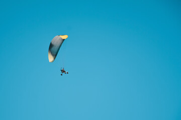 Paraglider flies with a parachute on an air motorcycle with a propeller. Man paragliding with motorized trike under clear sky. Air sports