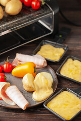 Delicious traditional Swiss melted raclette cheese on diced boiled or baked vegetables served in individual skillets