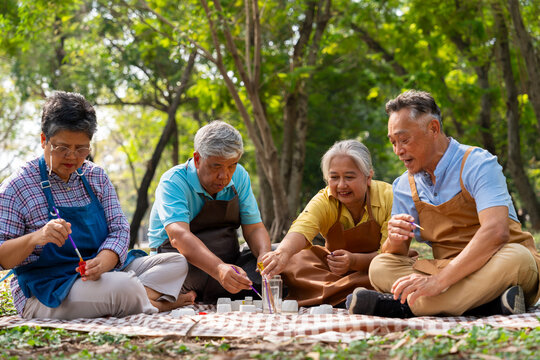 A group of Asian senior people enjoy painting cactus pots and recreational activity or therapy outdoors together  at an elderly healthcare center, Lifestyle concepts about seniority