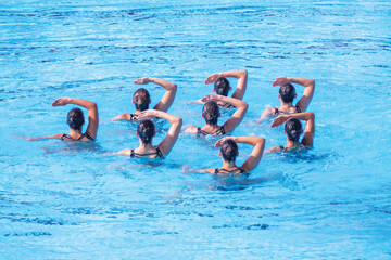 Synchronized swimmers team performing artistic swimming in the swimming pool