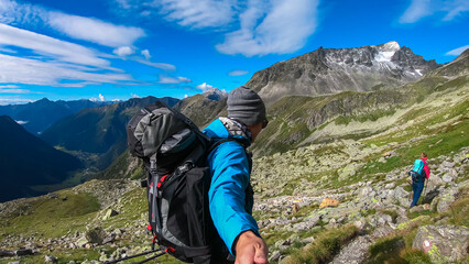 Naklejka premium Hiker couple on alpine meadow with panoramic view of majestic mount Gamskarlspitz in High Tauern National Park, Carinthia, Austria. Idyllic hiking trail in Austrian Alps. Wanderlust paradise Mallnitz