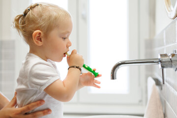 Young Child Practices Good Hygiene While Being Assisted By Her Parent