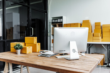 A wooden desk in an SME office, with a laptop, desktop computer, and a parcel cardboard box. The...