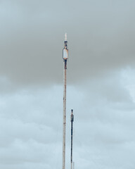 Stormy sky over old gas flare or flare stack with guy wires cables to holding up, exhaust fumes...