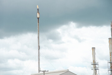 Obraz premium Stormy sky over old gas flare or flare stack with guy wires cables to holding up, exhaust fumes from crude oil refinery plant in San Antonio, Texas, major source air pollutants refined petroleum