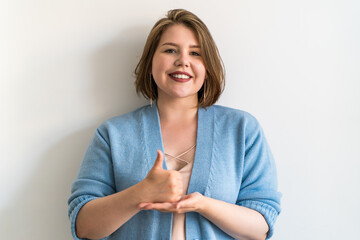 Plus size woman showing thumbs up sign in sign language, expressing approval and positivity....