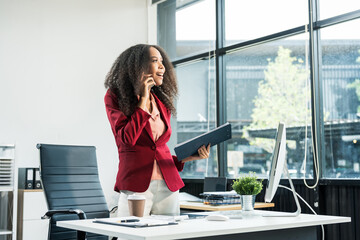 An African American woman with an afro works at a wooden desk in an office, focusing on business...