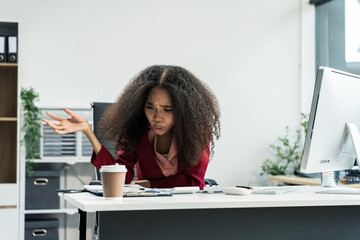 An African American woman with an afro works at a wooden desk in an office, focusing on business...