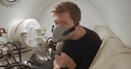 Military man receiving treatment in industrial hyperbaric chamber