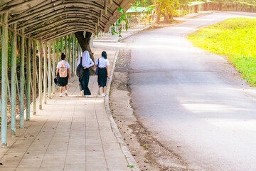 Cheerful muslim woman wearing hijab walking with her friend. Happy three asian female students friend in uniform walking together on footpath in campus. Multicultural female friends outdoors.Diversity