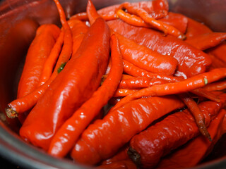 closeup of pile of big hot red chilies in a pan