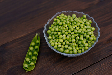Fresh green peas in bowl on wooden background. wooden table background
