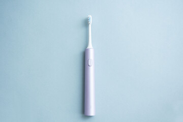 Electric toothbrush on blue background, top view. Oral care.	