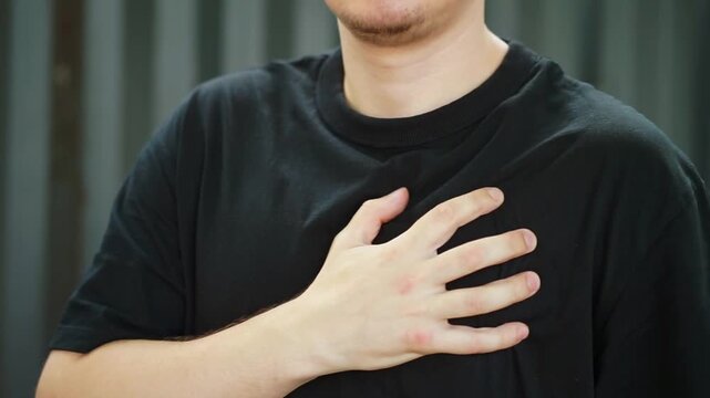 A man holds his hand on his heart.
A person is feeling unwell.
Husband has heart problems