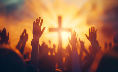 Hands raised in worship in front of a cross at sunset.