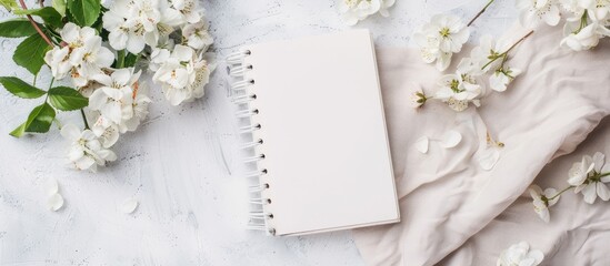Styled photo featuring a white notebook with copy space image decorated with flowers on a light background