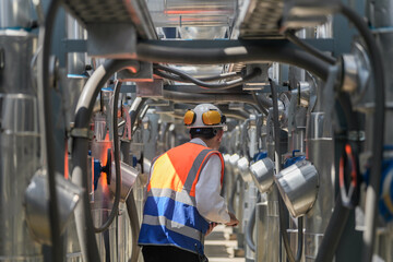 Engineers inspect gas and water pipes for power and cooling in industrial and building systems. workers in safety gear work seriously in oil and gas refining plant with pipes connecting to machinery.