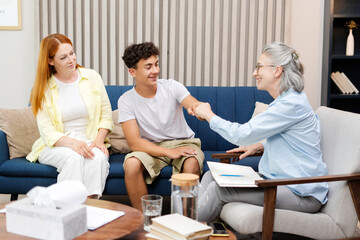 Fototapeta premium Happy teenage boy giving fist bump with therapist after successful therapy session