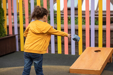 Cute little girl playing Corn hole bag toss game in a park outdoor