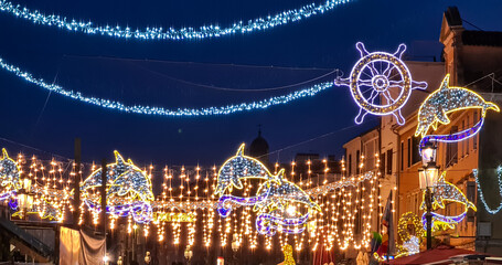 Display of decorative lights at night on the street Corso del Popolo during popular fish festival called Sagra del Pesce in Chioggia, Venetian Lagoon, Veneto, Italy. Touristic events in Italian summer