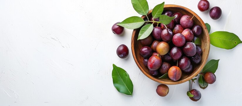 Ripe phalsa fruit in a wooden bowl with leaves isolated on a white background emphasizing a top view with selective focus and copy space image