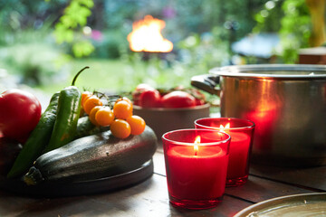 still life on a garden table with candles and a plate of vegetables