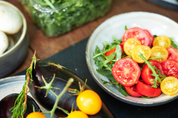 red peppers, mushrooms, tomatoes and herbs lay on a wooden table