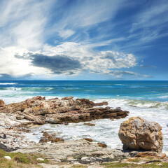 Ocean, water and rocks in nature outdoor for travel destination, coat environment and natural beauty. Blue sky, beach and scenery for seaside peace, tourism journey with adventure location of view