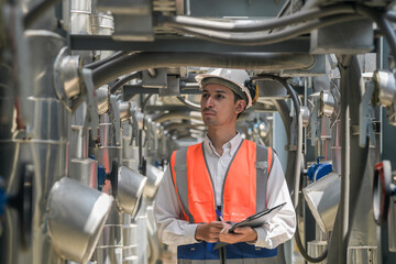 Engineers inspect gas and water pipes for power and cooling in industrial and building systems. workers in safety gear work seriously in oil and gas refining plant with pipes connecting to machinery.