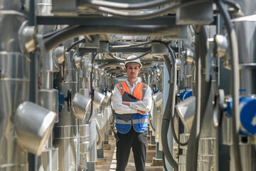 Engineers inspect gas and water pipes for power and cooling in industrial and building systems. workers in safety gear work seriously in oil and gas refining plant with pipes connecting to machinery.